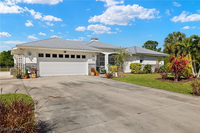 ranch-style house with a garage, driveway, metal roof, a front lawn, and stucco siding