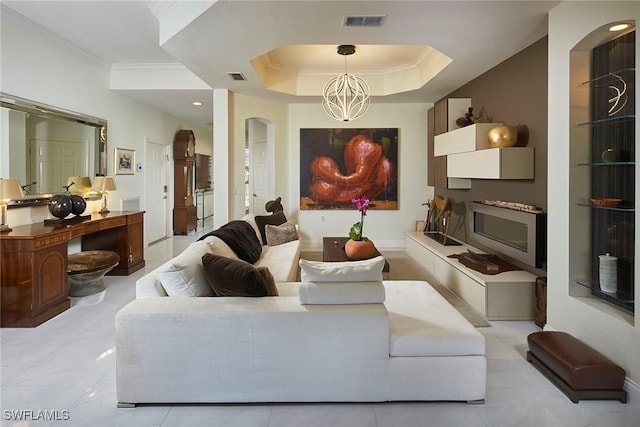 living room featuring an inviting chandelier, ornamental molding, and a tray ceiling