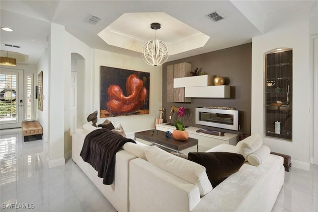 living room with crown molding, a raised ceiling, and a notable chandelier