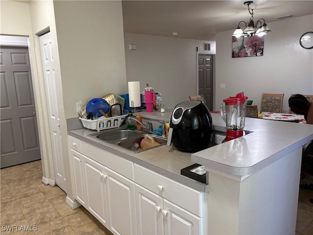 kitchen featuring white cabinetry, sink, and decorative light fixtures