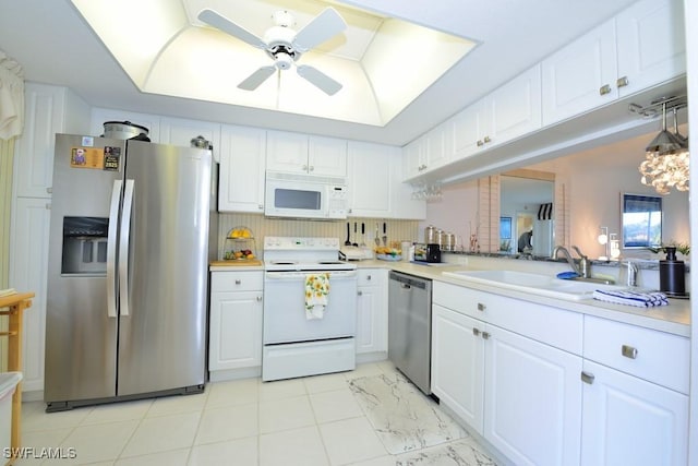 kitchen featuring a raised ceiling, appliances with stainless steel finishes, sink, and white cabinets