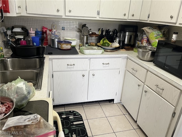 kitchen featuring white cabinets, light tile patterned flooring, sink, and backsplash