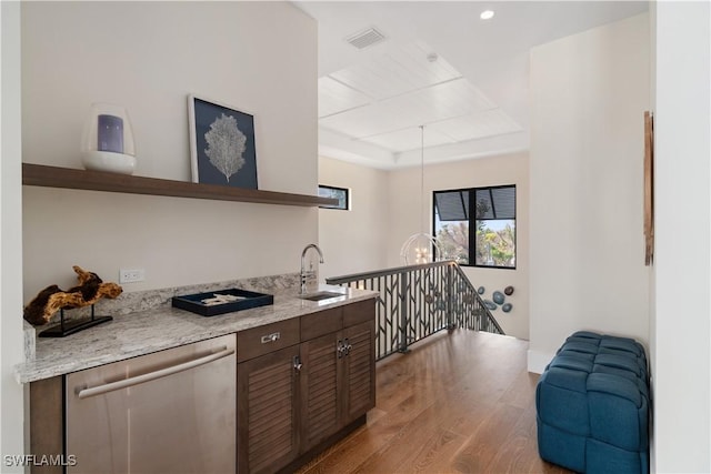 kitchen featuring light stone counters, dark brown cabinets, a tray ceiling, dishwasher, and light hardwood / wood-style floors