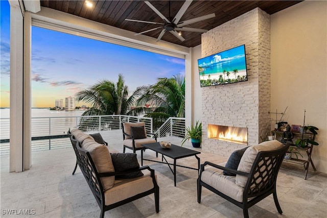 patio terrace at dusk featuring an outdoor living space with a fireplace and ceiling fan