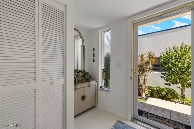 doorway with baseboards and light tile patterned floors