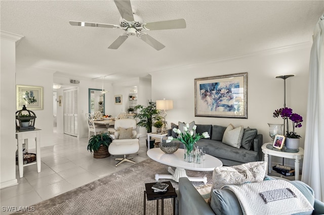 living area with light tile patterned floors, visible vents, a ceiling fan, a textured ceiling, and crown molding