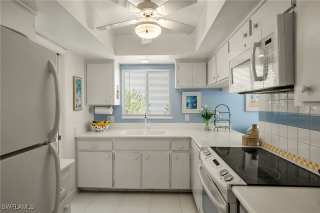 kitchen featuring white appliances, light countertops, a sink, and white cabinets