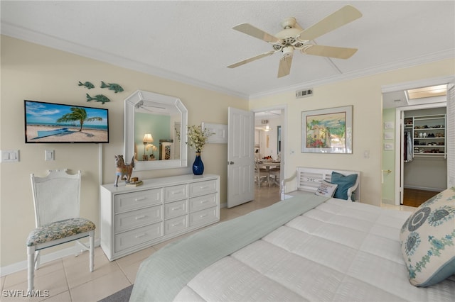 bedroom featuring light tile patterned floors, a spacious closet, visible vents, and crown molding