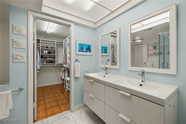 bathroom with a spacious closet, double vanity, a sink, and visible vents