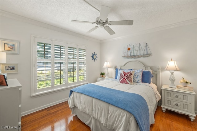 bedroom featuring crown molding, a textured ceiling, baseboards, and wood finished floors