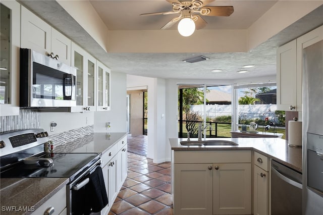 kitchen with appliances with stainless steel finishes, tasteful backsplash, sink, white cabinets, and tile patterned floors