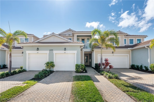 townhome / multi-family property featuring a garage, a balcony, and decorative driveway