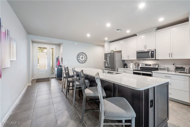 kitchen featuring a center island with sink, visible vents, appliances with stainless steel finishes, light countertops, and white cabinetry