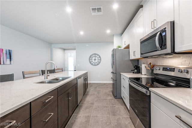 4688 Arboretum Cir Unit 102, Naples, FL 34112 - kitchen with appliances with stainless steel finishes, a sink, white cabinets, decorative backsplash, and light stone counters