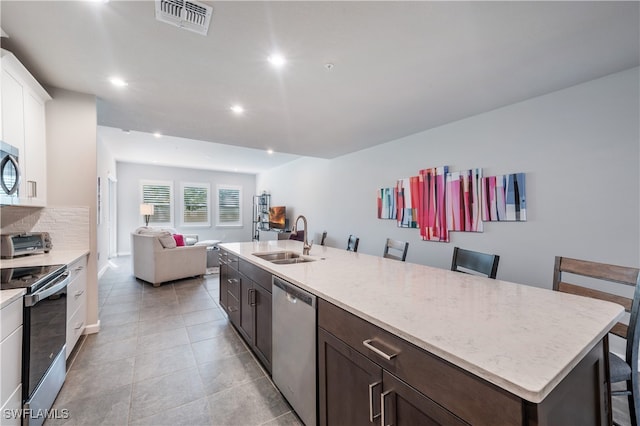 4688 Arboretum Cir Unit 102, Naples, FL 34112 - kitchen featuring appliances with stainless steel finishes, a sink, dark brown cabinetry, recessed lighting, and open floor plan