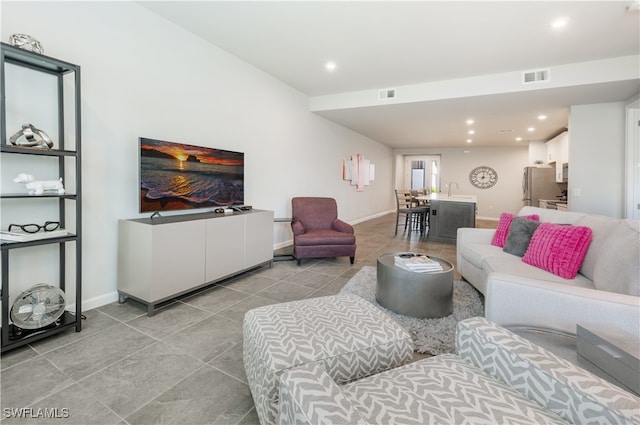 living room featuring baseboards, light tile patterned flooring, visible vents, and recessed lighting