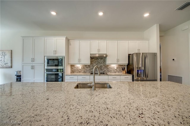 kitchen with wall oven, stainless steel fridge with ice dispenser, white cabinetry, and light stone counters