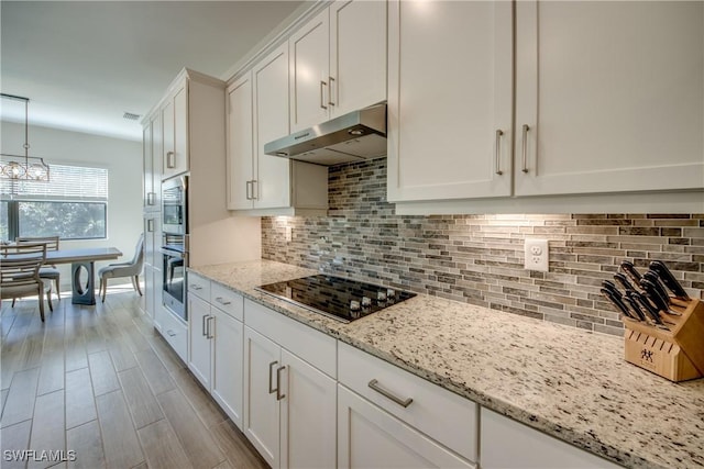 kitchen featuring white cabinetry, light stone counters, hanging light fixtures, black electric stovetop, and oven