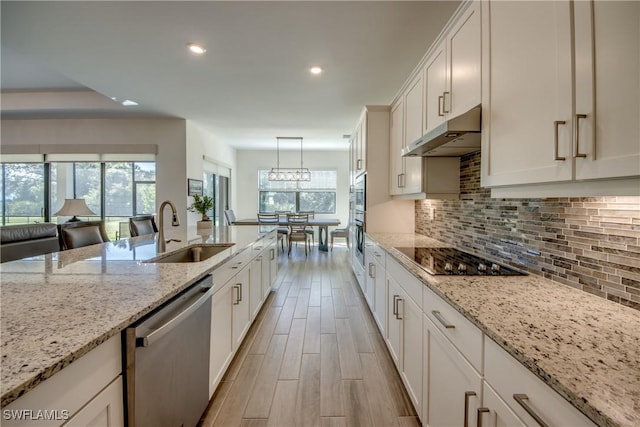 kitchen with dishwasher, sink, hanging light fixtures, black electric stovetop, and light stone counters