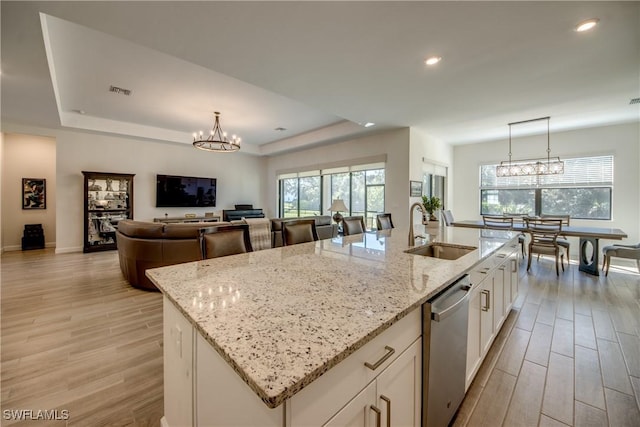 kitchen featuring an island with sink, white cabinets, an inviting chandelier, and decorative light fixtures