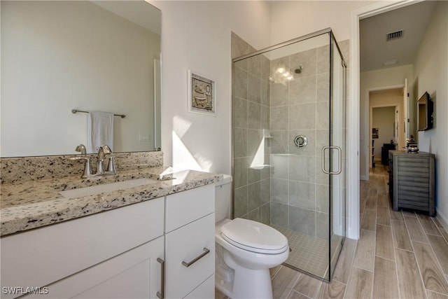 bathroom with vanity, toilet, and a shower with shower door