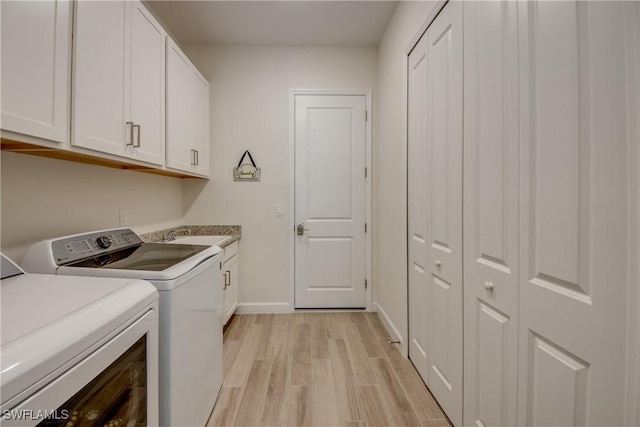 clothes washing area featuring light hardwood / wood-style flooring, sink, washer and clothes dryer, and cabinets