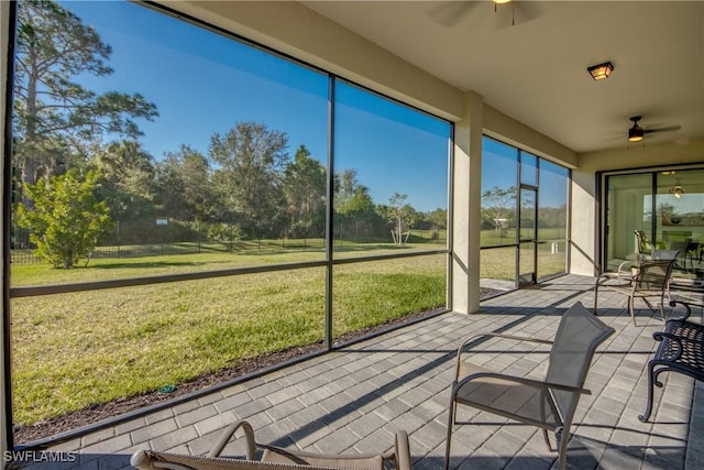 unfurnished sunroom featuring ceiling fan