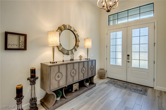 entrance foyer with a notable chandelier, light hardwood / wood-style floors, and french doors