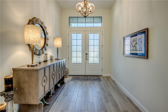 entryway with an inviting chandelier, wood-type flooring, and french doors