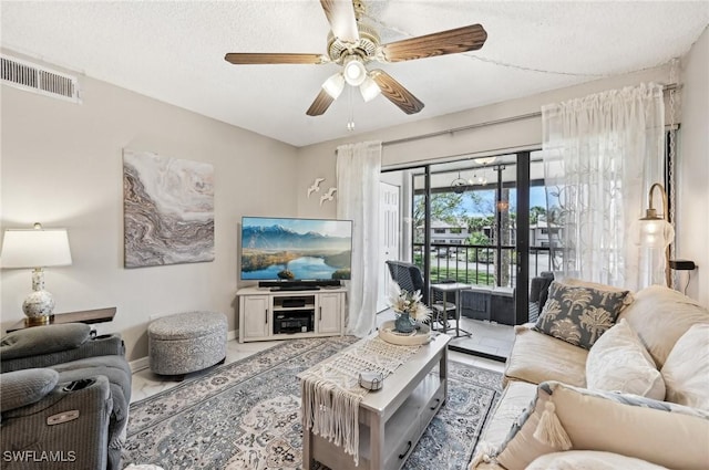 living room featuring ceiling fan and a textured ceiling