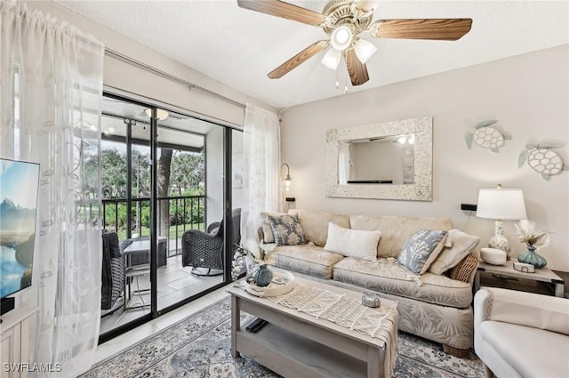 living room featuring ceiling fan and a textured ceiling