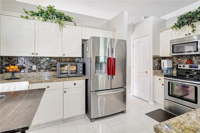 kitchen with light stone counters, tasteful backsplash, stainless steel appliances, and white cabinets