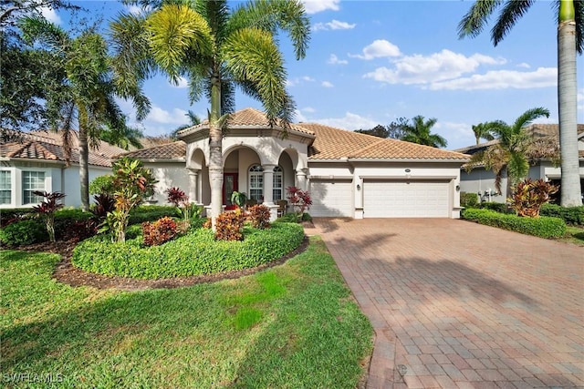 mediterranean / spanish home featuring a garage and a front lawn