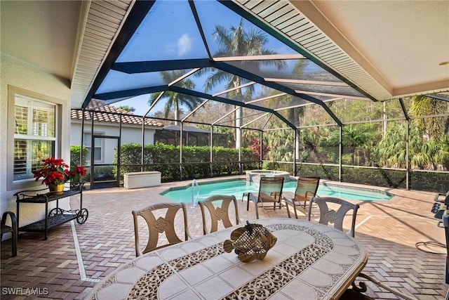 view of patio / terrace featuring a swimming pool with hot tub and glass enclosure