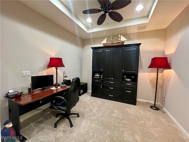 office space featuring a tray ceiling, ceiling fan, and light carpet