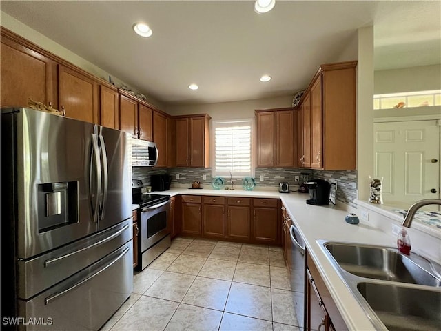 kitchen featuring sink, backsplash, appliances with stainless steel finishes, and light tile patterned floors