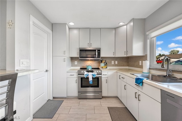 kitchen with stainless steel appliances, tasteful backsplash, sink, and white cabinetry