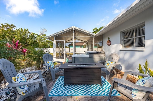 view of patio with a fire pit, a hot tub, and a sunroom