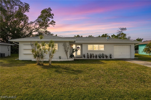 single story home with central AC unit, a garage, and a lawn