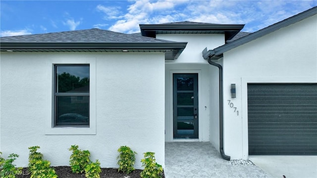 view of side of home with stucco siding, roof with shingles, and an attached garage