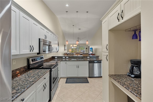 kitchen featuring stainless steel appliances, light tile patterned flooring, a sink, and dark stone countertops