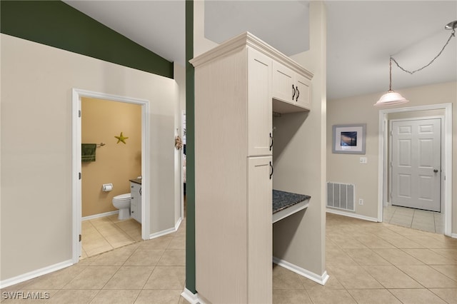 interior space featuring tile patterned flooring, toilet, visible vents, baseboards, and vaulted ceiling