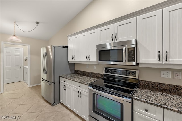 kitchen featuring lofted ceiling, light tile patterned flooring, stainless steel appliances, white cabinetry, and dark stone countertops