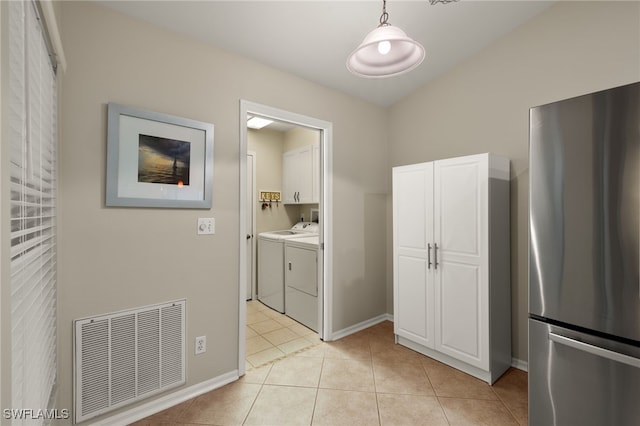 laundry area with light tile patterned floors, cabinet space, visible vents, washer and dryer, and baseboards