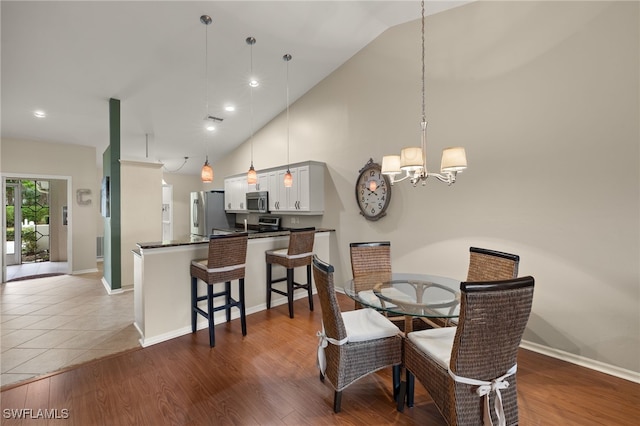 dining room with high vaulted ceiling, baseboards, and wood finished floors