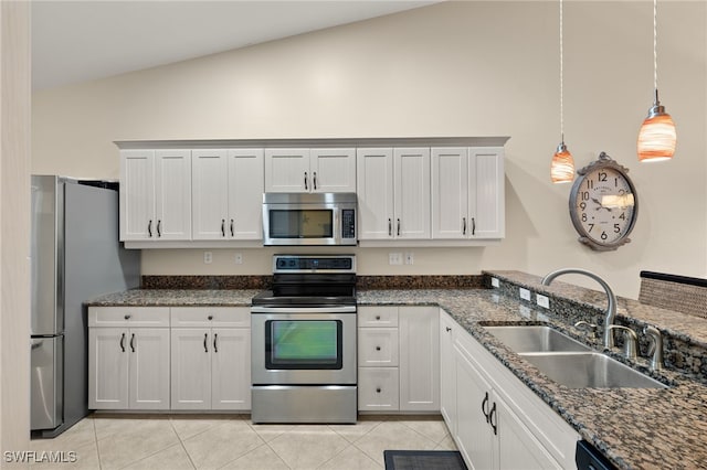 kitchen featuring decorative light fixtures, stainless steel appliances, light tile patterned flooring, vaulted ceiling, and a sink