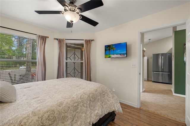 bedroom featuring freestanding refrigerator, ceiling fan, baseboards, and wood finished floors