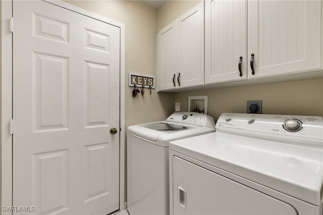 washroom featuring cabinet space and washer and clothes dryer