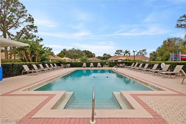 community pool with a patio area and fence