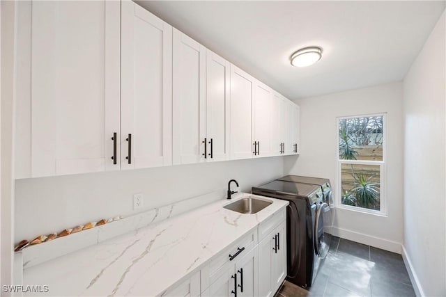 clothes washing area featuring cabinets, separate washer and dryer, sink, and dark tile patterned flooring